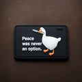 PVC patch with a white goose holding a knife and the text ‘Peace was never an option’ on a rectangular background.