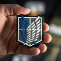 Close-up of Attack on Titan PVC morale patch with blue and white winged emblem held in a hand
