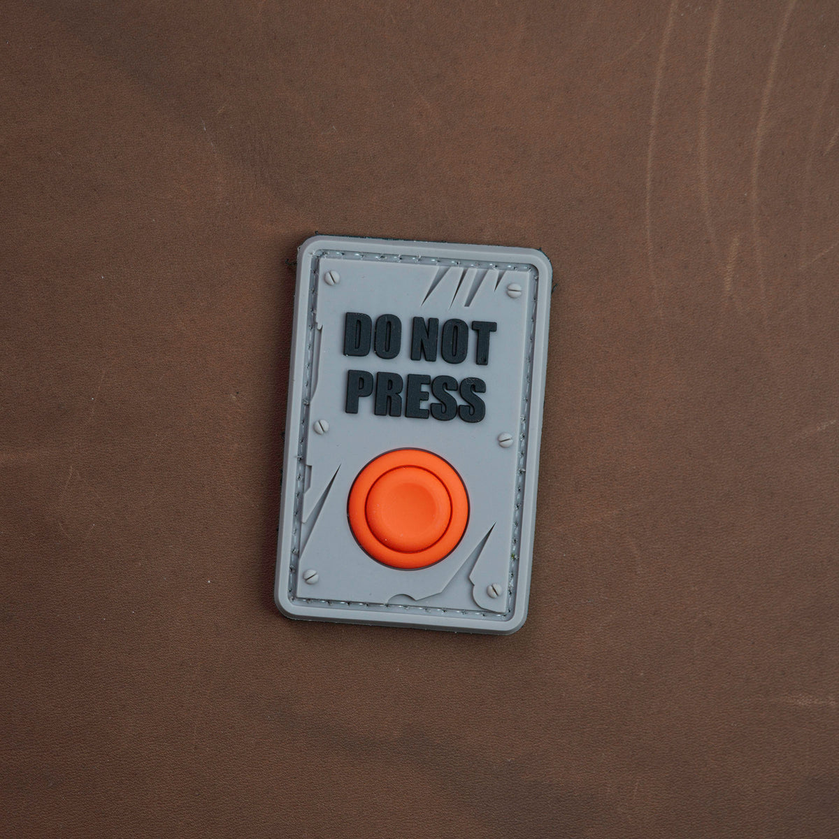 Grey Do Not Press PVC morale patch with orange 3D button detail
