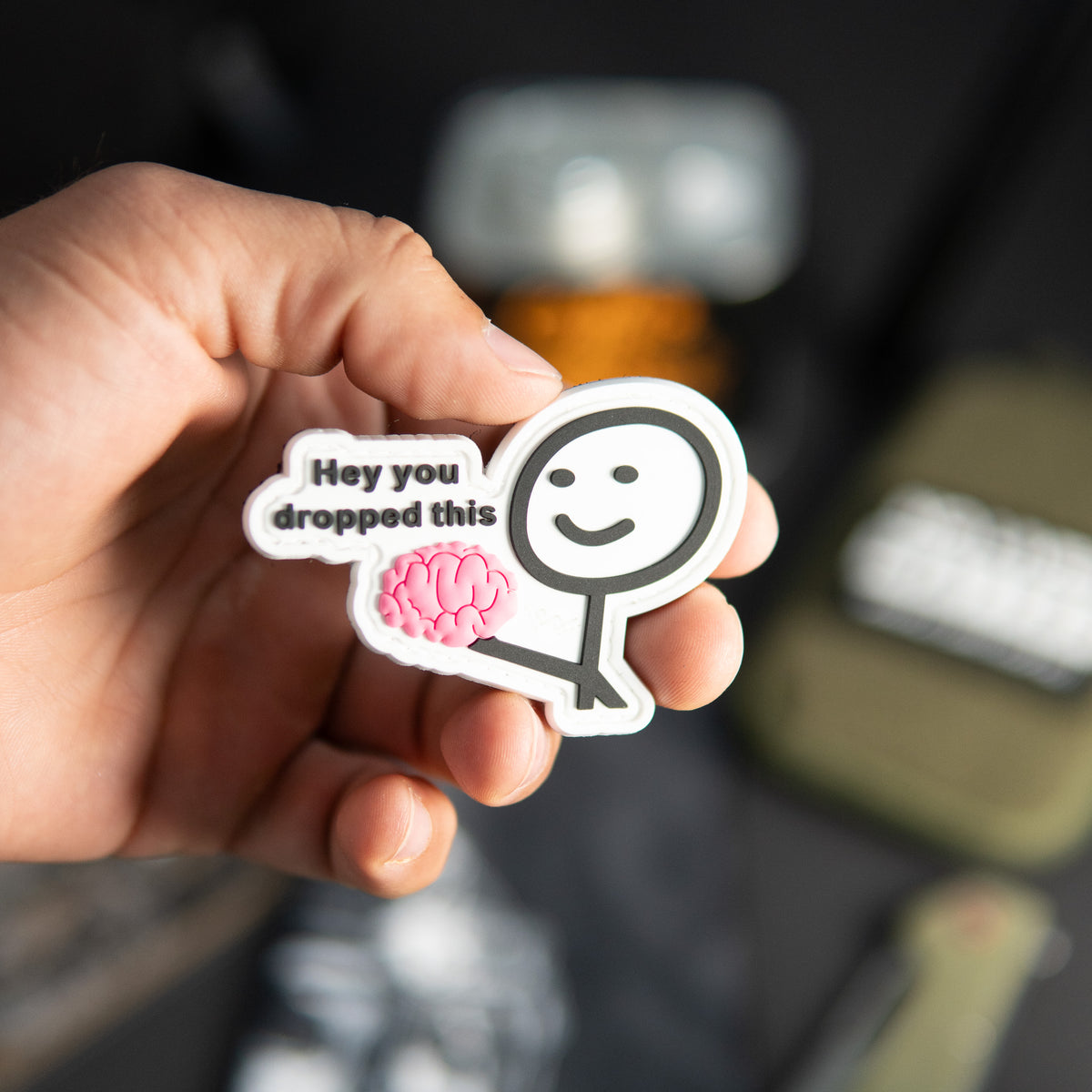 Hey You Dropped This PVC morale patch with pink brain design held in a hand