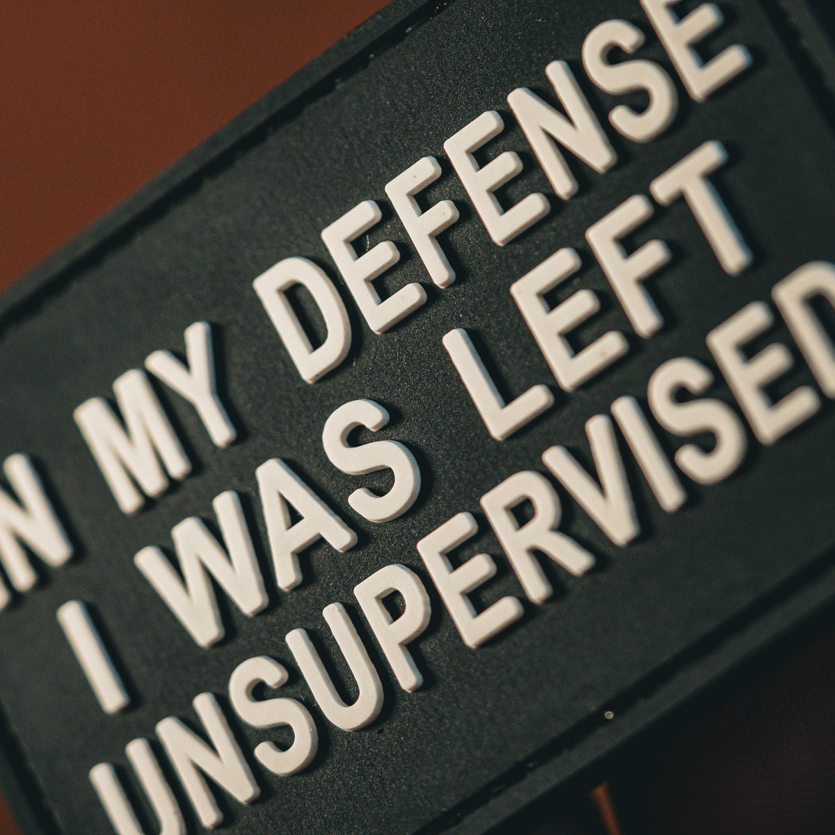 Close-up of Left Unsupervised PVC morale patch with raised white text